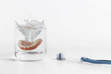 Pflegetipps für Zahnersatz. Prothese in Glas mit Wasser.